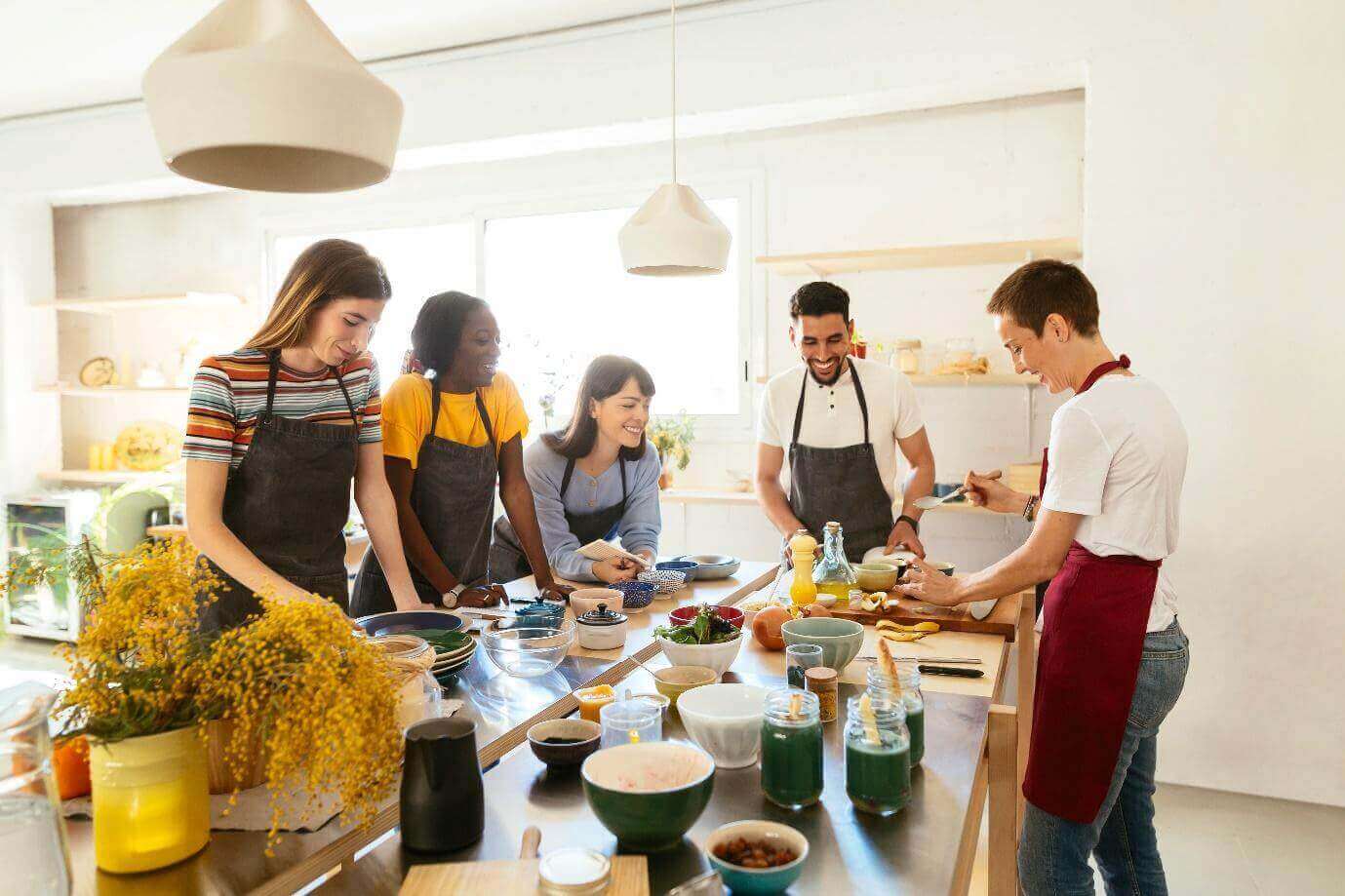 Spanish Cooking Classes in Barcelona.Tourists and chef in a cooking workshop preparing food.