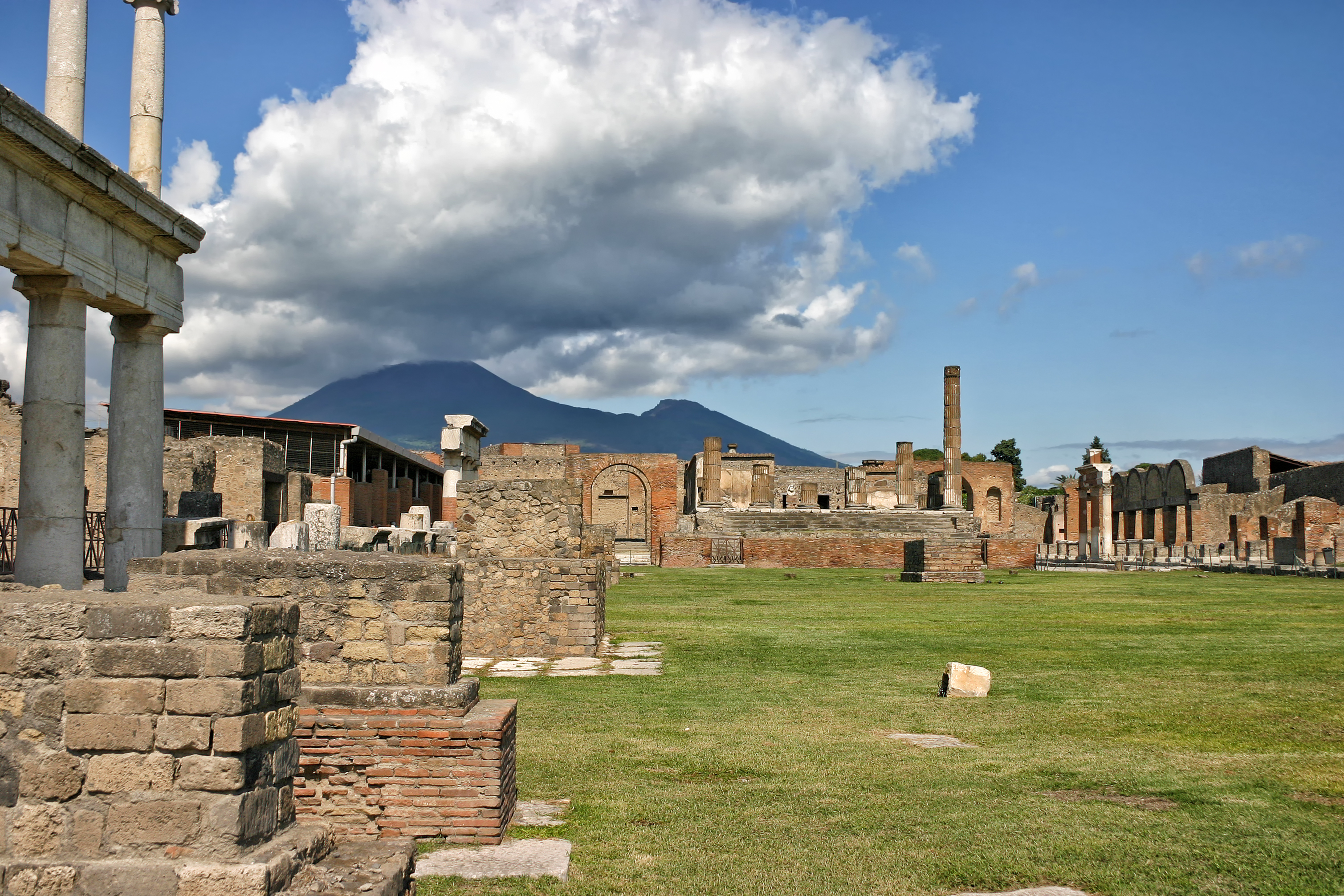 View of the ruins of Pompeii from inside the Forum with the Jewish Temple in the center, the Granary to the left and the Market to the right and Mount Vesuvius in the background.